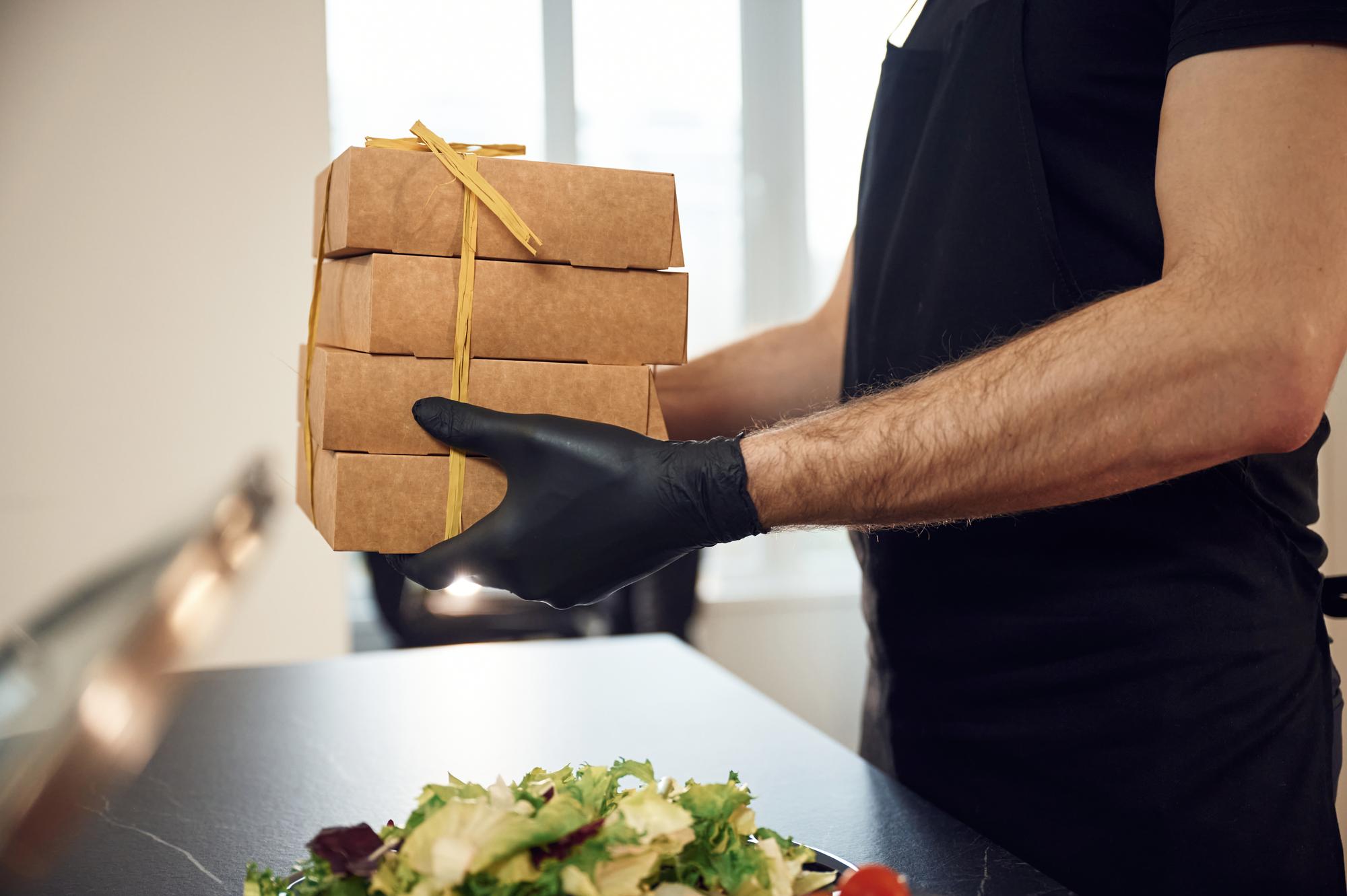 Chef handing over boxed menus to client at doorstep